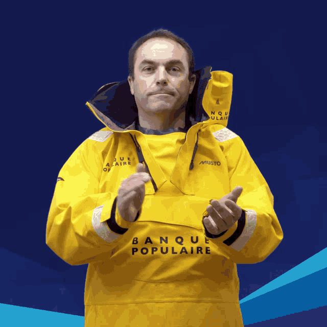 a man wearing a yellow banque populaire jacket clapping his hands