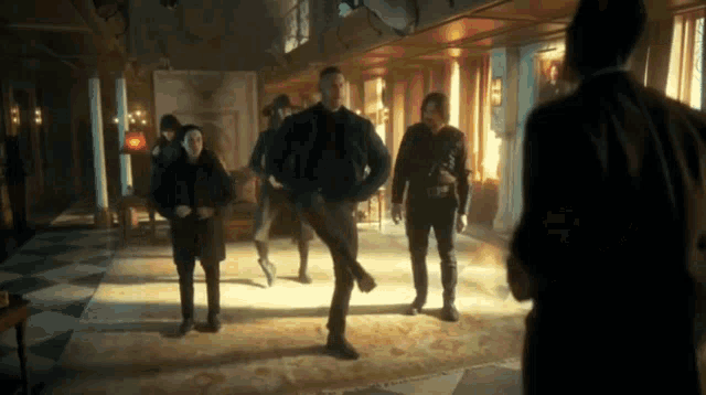 a group of people are standing in a dark room and one of them is kicking another person
