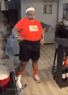 a man in a red nike shirt is dancing in a kitchen