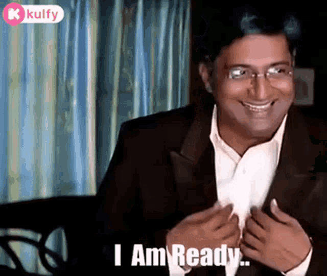 a man in a suit and glasses is smiling and saying `` i am ready `` .