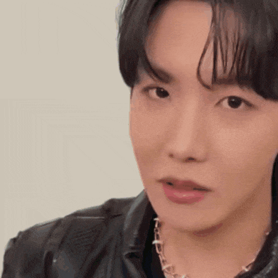 a close up of a person 's face wearing a leather jacket and a necklace .