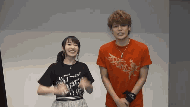 a man and a woman standing next to each other wearing king of super live shirts