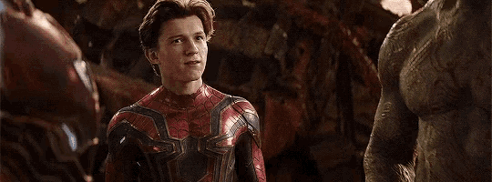 a man in a spiderman suit is standing next to a statue of a man in a suit .