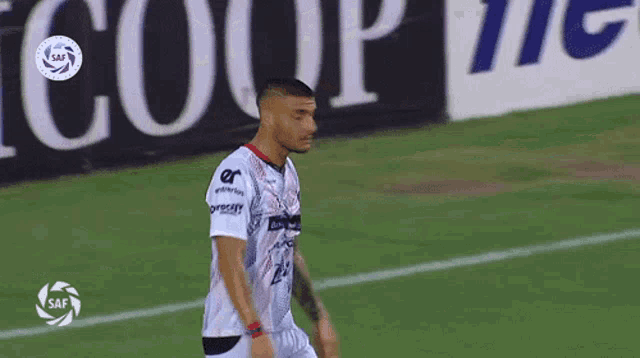 a soccer player stands on a field in front of a sign that says coup