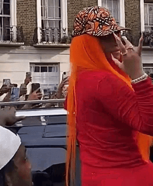 a woman wearing a red shirt and a hat is taking a picture of herself with her cell phone .