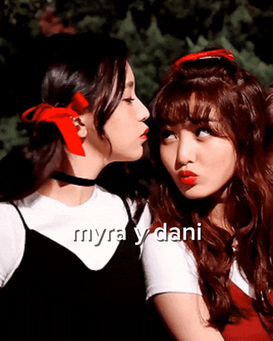 two girls with red ribbons in their hair are kissing each other with the words myra y dani below them