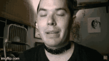 a man wearing a black shirt and a choker is making a funny face .