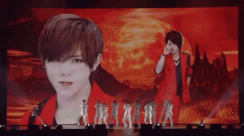 a group of people are standing on a stage in front of a large screen with a picture of a man on it .