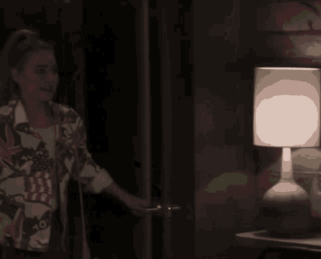 a woman in an american flag shirt stands in a dark room
