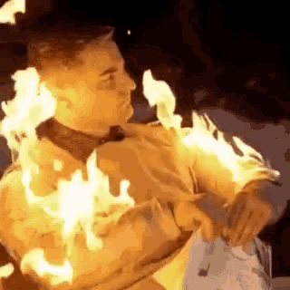 a man is covered in flames while holding a fork in his hand .