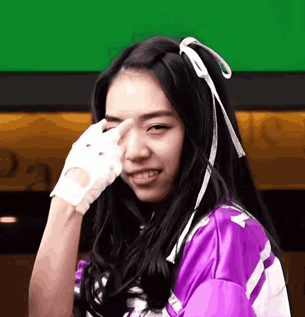 a girl wearing a purple jacket and white gloves is covering her eyes