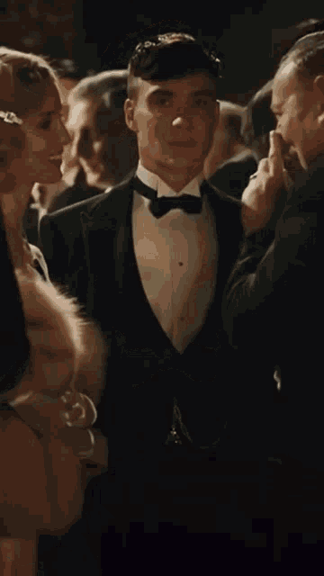 a man in a tuxedo is standing in a crowd of people