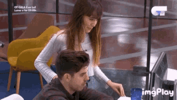 a man and a woman are sitting at a table with a computer monitor .