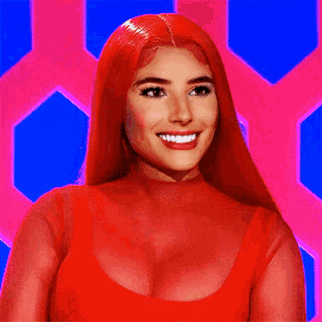 a woman with red hair is smiling and wearing a red top .
