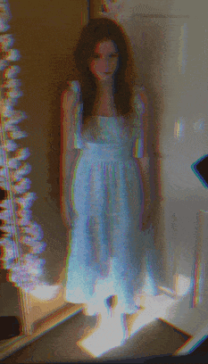a woman in a light blue dress is standing in front of a mirror