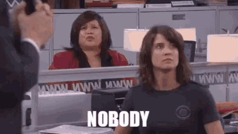 a woman is sitting at a desk in an office with the words `` nobody '' written on it .