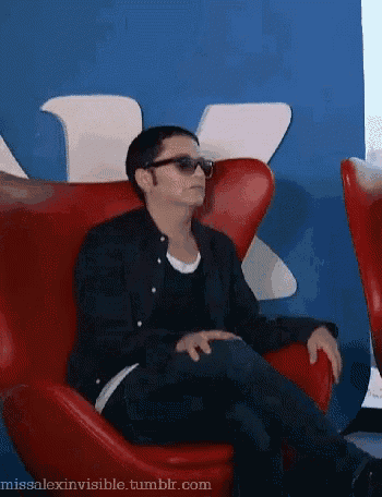 a man in sunglasses is sitting in a red chair .