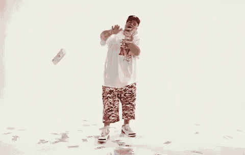 a man in a white shirt and red shorts is standing in a pile of money .