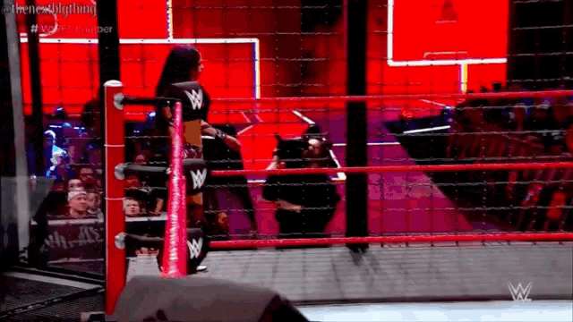 a woman is standing in a wrestling ring with a w logo on her shirt .