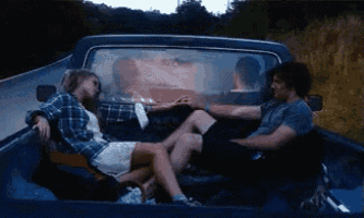 a man and a woman are holding hands in the back of a truck