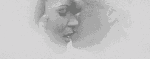 a black and white photo of two women kissing each other on the forehead .