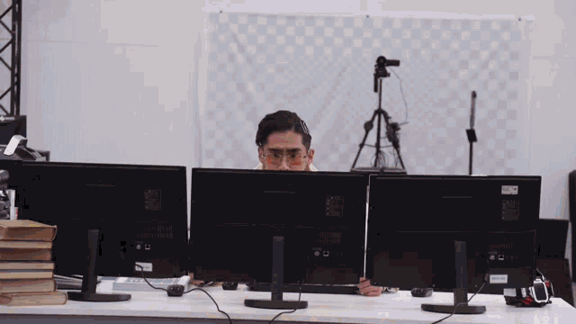 a man wearing glasses is sitting in front of a computer monitor