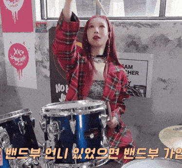a girl with red hair is playing drums in front of a sign that says nop