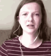 a woman wearing headphones and a striped shirt is making a sad face .