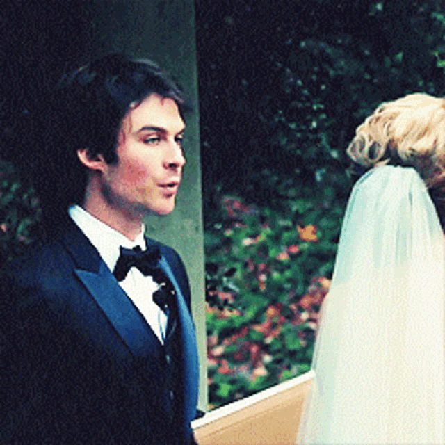 a man in a tuxedo stands next to a woman in a white dress