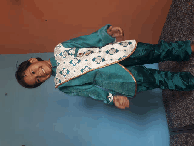 a little boy wearing a green and white outfit smiles
