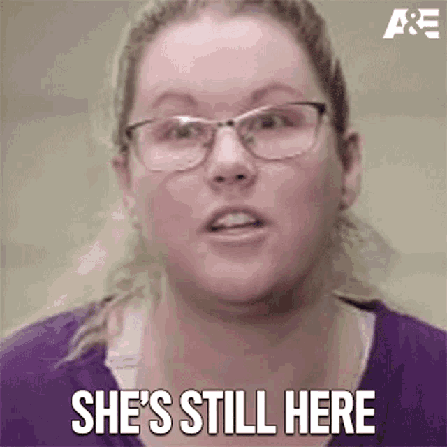 a woman wearing glasses and a purple shirt says she 's still here