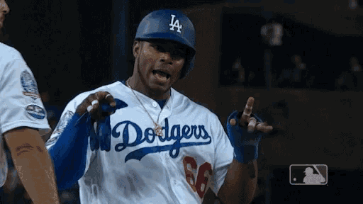 a man wearing a dodgers jersey and helmet is talking to another man