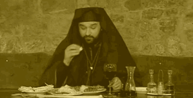 a man is sitting at a table eating and drinking