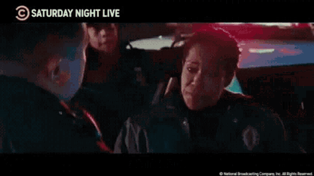 a woman in a police car is talking to a man and says pretty sure i died i 'm definitely dead