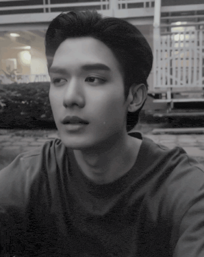 a black and white photo of a young man wearing a t-shirt that says adidas on it