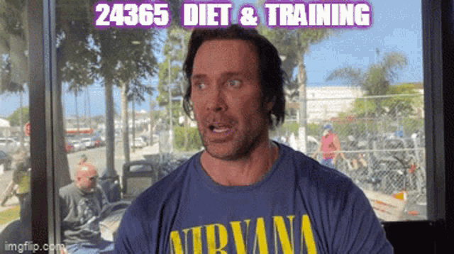 a man wearing a blue shirt that says nirvana is talking