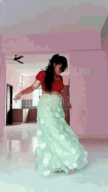a woman in a green skirt is dancing in an empty room