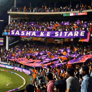a stadium full of people with purple flags and a banner that says sasha ke sitare