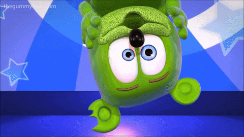 a green gummy bear is upside down on a blue surface