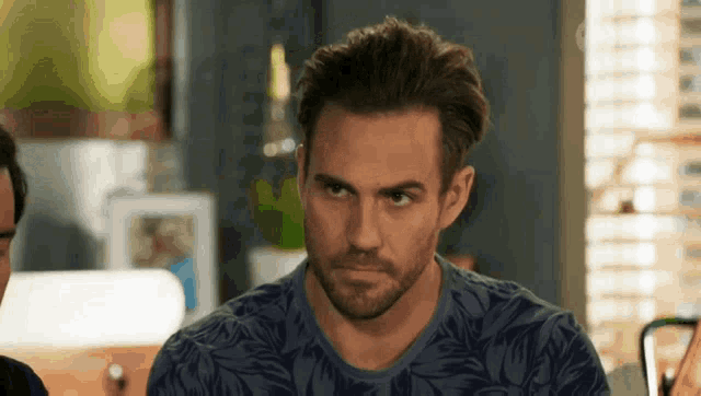 a man with a beard is wearing a blue shirt with a floral pattern