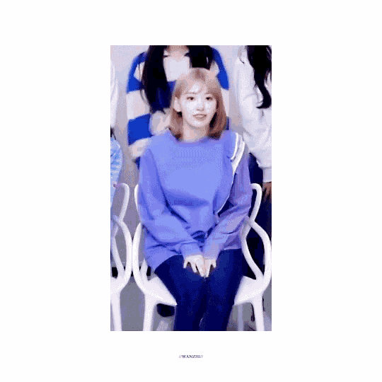 a girl in a purple sweater is sitting on a chair