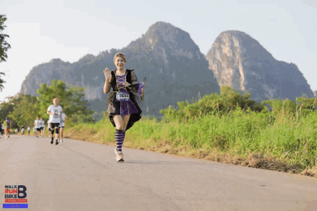 a woman is running in a walk and bike race with mountains in the background