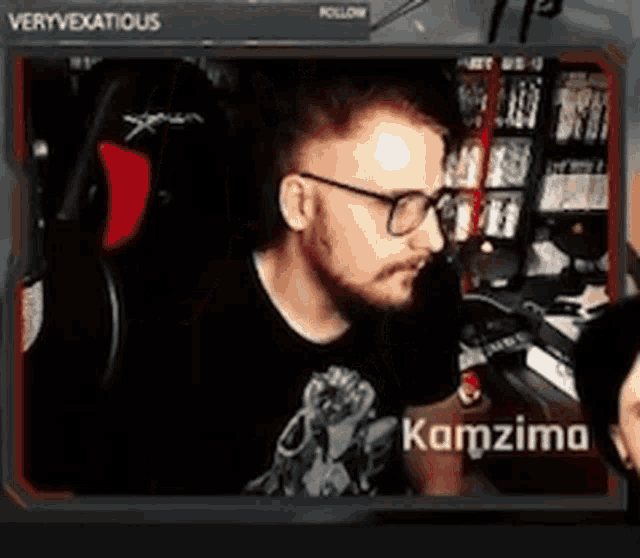 a man with a beard and glasses is sitting in a chair in front of a computer screen .