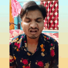 a man with a beard and a floral shirt is making a funny face .