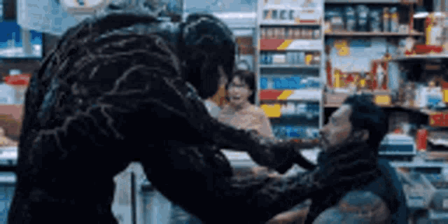 venom is fighting a man in a store in a movie .