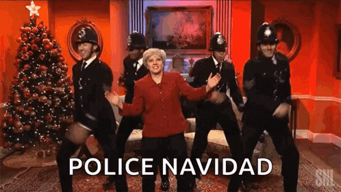 a group of police officers are dancing with a woman in front of a christmas tree ..