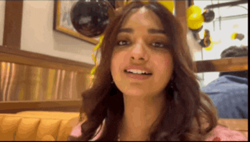 a close up of a woman 's face with balloons in the background