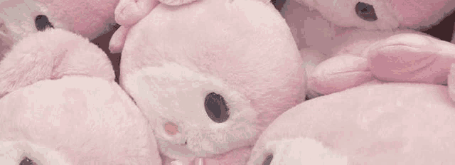 a bunch of pink stuffed animals are laying on top of each other on a table .
