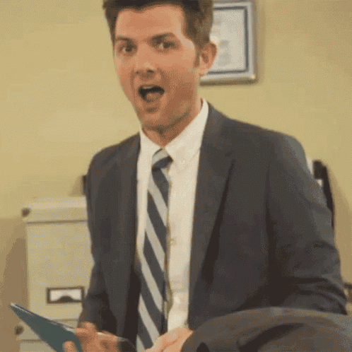 a man in a suit and tie is holding a clipboard with his mouth open .