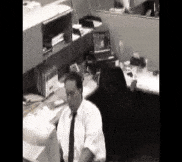 a man in a white shirt and black tie sits at a desk